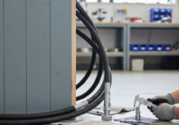 Hydraulische slangen en koppelingen naast gecontroleerd en hersteld schilderwerk op een houten constructie.